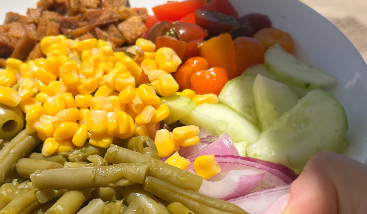 Insalatona con tempeh saltato, pomodorini tricolore, mais, fagiolini, olive verdi, cipolla di Tropea e cetriolo